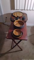 Overview of the dining set including stacked plates, cups and saucers on two wooden tables with cream walls in background.