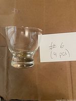 Single clear thick-based glass with rounded lip, showing size and shape.