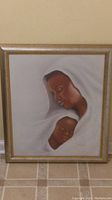 Full view of framed wall picture with mother and child wrapped in white cloth.