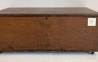 Full front view of antique wooden sea chest showing its dovetailed construction and original patina. The chest rests on four small wheels.