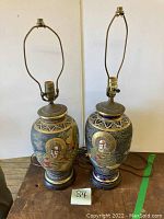 Pair of antique Japanese Satsuma lamps standing side by side showing overall form and lamp fittings.