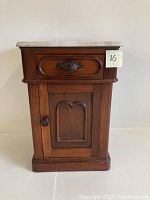 Full front view of oak end table with marble top and cabinet door closed