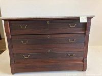 Full frontal image of the antique dresser showing white marble top and four wooden drawers with brass handles.