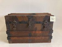 Front view of the antique steamer trunk showing wood panels and metal reinforcements along with locks and latches.