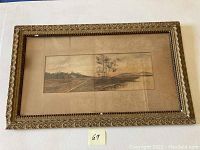 Full view of watercolor painting on board in ornate gold-colored frame with glass, depicts countryside landscape.