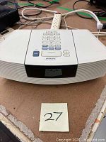 Front and top view of white Bose Wave Radio/CD with remote on top