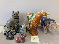 Full view of the lot showing all ceramic animal figurines including cats, horse, elephant and small animals.