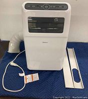 Front view showing white Shinco air conditioner unit with power cord, vent hose, and window bracket.