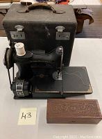 Front view of Singer Featherweight sewing machine in black case with wooden Wheeler & Wilson sewing box in front.