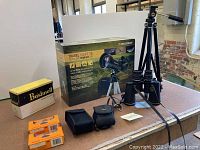 Celestron TravelScope 70 telescope in original box, Bushnell and Sears binoculars with cases, two orange boxed disposable cameras on table