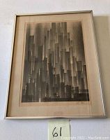 Framed black and white cityscape artwork in chrome frame with glass, showing entire framed piece on a wall.