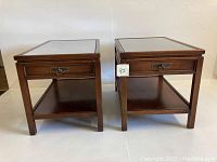 Front view of the pair showing the wooden frame, drawer, drawer handle, and lower shelf.