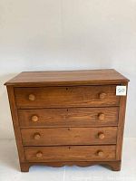 Front view of vintage pine chest of drawers showing four drawers with wooden knobs and two keyholes without keys.