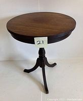 Front perspective showing round top and pedestal base with three curved legs