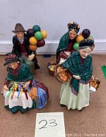 Set of four vintage Royal Doulton balloon holding figurines displayed on a table, showing all figures together.