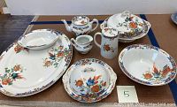 Full view of all china pieces arranged together on a tabletop showing serving platters, bowls, and tea set.