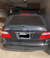 Rear view of black wagon showing Mercedes badge, E320 model badge, rear hatch and taillights