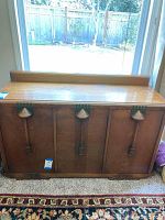 View of front of oak Art Deco buffet showing three cabinet doors with decorative wooden handles with green accents.