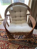 Front view of bent branch arm chair with cream tufted cushion placed on a patterned carpet.