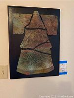 Frontal view of framed ceramic artwork mounted on wood showing full piece and frame.