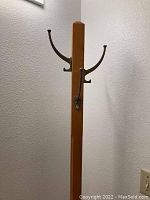 Wooden hall tree coat rack with brass hooks on upper part, natural wood finish shown in detail