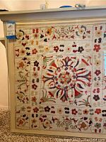 Full view of embroidered textile art in acrylic frame showing overall pattern and condition.