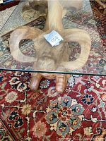 Close-up of water buffalo carved base under glass top on ornate carpet