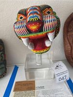 Front angled view of jaguar head showing detailed multicolored beading and open mouth with teeth on clear acrylic stand.