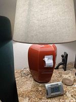 Photo of hexagonal cinnamon finish lamp with beige shade, electrical cord visible, sitting on granite tabletop.