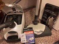 Simplicity canister vacuum with powerhead attachment, charcoal filters, and vacuum bags on carpeted floor