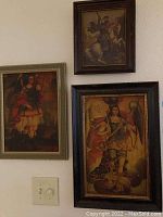 Three framed canvas art pieces hung on a white wall showing medieval or earlier themes with dark muted colors.