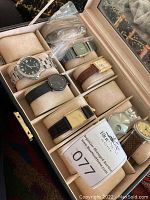 Open Wollf watch storage box showing leather exterior, sueded watch pads, and six wristwatches arranged inside