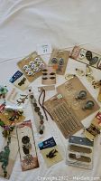 Photo of mixed craft embellishments including metal number tags, owl and dragonfly charms, decorative gears, and beaded tassels.