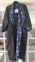 Photo of the robe showing black side with navy blue floral motif trim, deep V neck, and long sleeves.