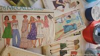 Photo showing vintage 1960s McCalls pattern 5548 displaying various illustrated dress and top fashions, with part of ribbon reels visible