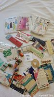 Overview photo showing maternity sewing patterns, various sewing threads, belt buckles, trims, and sewing accessories arranged on a table.