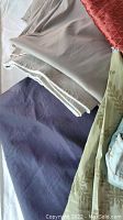 Lot of 5 sewing fabrics laid out on a surface showing different textures and colors including beige, purple, olive green, red, and blue pieces.