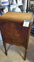 Full view of solid wood vintage radio cabinet showing carved detailing on front and turned legs