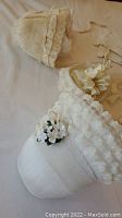 Photo showing lace detailed white hats and small gathered fabric purse with flowers