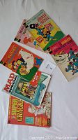 Photo shows all six comic books spread out on a white surface, including MAD magazines, Hanna Barbera and Terrytoons comics, and a Harlem Globetrotters comic.