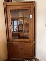 Front view of cabinet showing upper glass-paned door and lower wooden doors