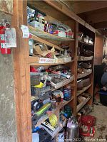 Wooden shelves filled with assorted hardware boxes, tool parts, and containers, including labeled boxes and metal items.