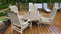 Outdoor firepit table and four mesh deck chairs arranged on a wooden deck, showing overall condition and setup.