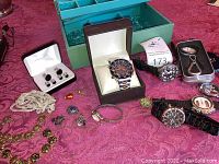 Overview of three wristwatches, necklaces, cufflinks, earrings, ring and bolo tie arranged on table