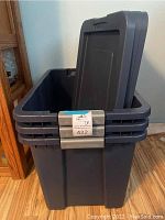 Photo showing stacked dark gray Sterilite storage tubs with one lid removed, displaying interior and locking lid mechanism