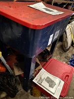 Blue and red parts washer basin showing body and lid, manual on lid.