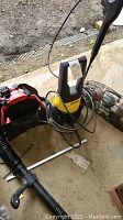 Karcher power washer with power cord and wand on floor next to leaf blower parts