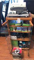 Wooden entertainment cabinet with Xbox 360, Kinect and other electronics piled on top and inside in multiple shelves