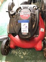 Top view showing Briggs & Stratton 675 series engine label on red push mower deck, front wheels visible