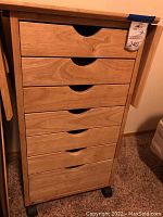 Front view of rolling craft table showing six drawers with cut-out handles and caster wheels.